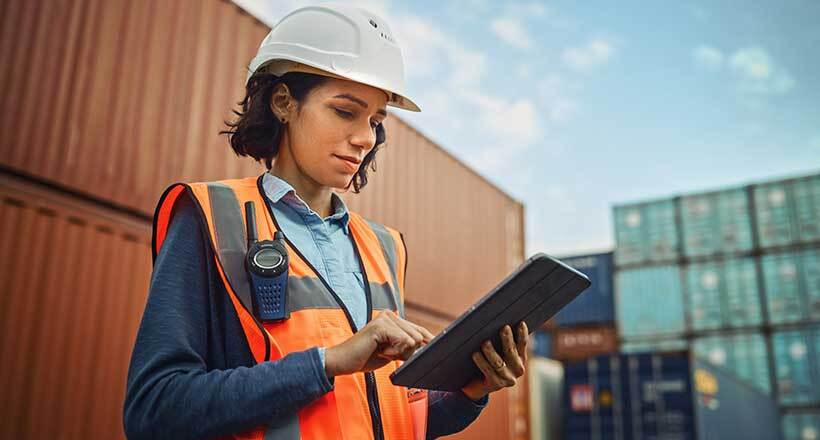 Female Industrial Engineer in White Hard Hat, High-Visibility Vest Working on Tablet Computer. Inspector or Safety Supervisor overseeing emergency preparedness operations and critical security operations.